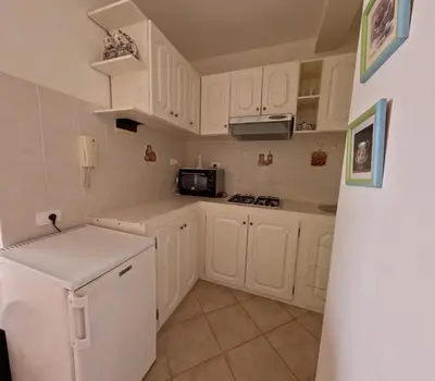 a small kitchen with white cabinets and a refrigerator at Ca' Ale in Santa Maria