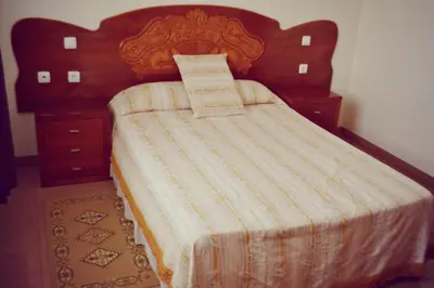 a bedroom with a bed with a wooden headboard at Residencial Cosmos in Assomada