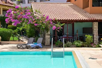 a swimming pool with two chairs and purple flowers at Porto Antigo II Poolside Appartment in Santa Maria