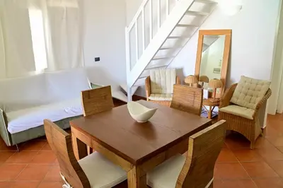 a living room with a wooden table and chairs at Porto Antigo II Poolside Appartment in Santa Maria