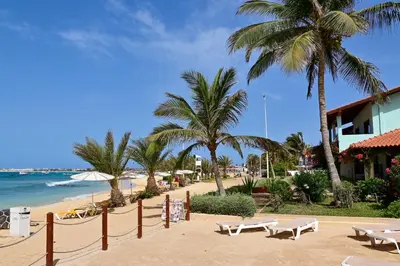 a beach with chairs and palm trees and the ocean at Porto Antigo II Poolside Appartment in Santa Maria