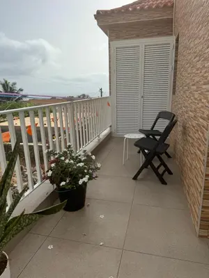a balcony with a chair and a table and flowers at Casa Carveiros Panoramic 360 in Tarrafal