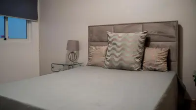 a bedroom with a bed with a headboard and pillows at Prainha Beach Apartment I in Praia