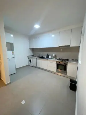 an empty kitchen with white cabinets and a stove at Prainha Beach Apartment I in Praia