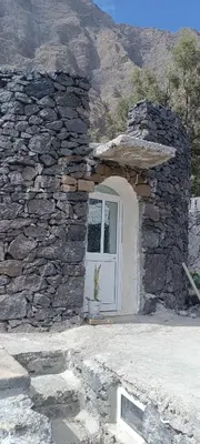 a stone building with a white door and a stone wall at Casa Mamã in Portela
