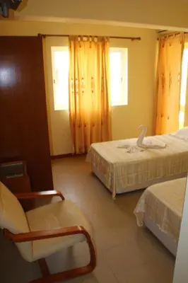 a room with two beds and a chair in it at Hotel Lazareto in Mindelo