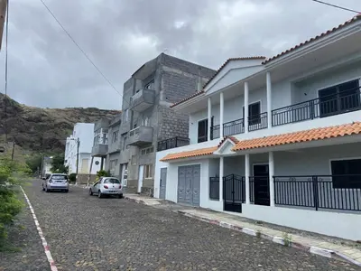 a street with two cars parked in front of buildings at Casa Magui e Cláudio in Tarrafal