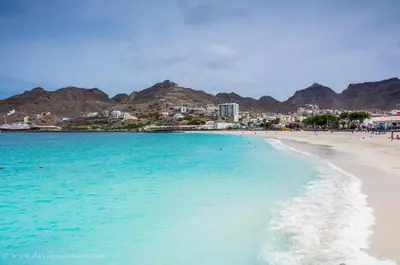 a beach with blue water and mountains in the background at Casa Maré & Museu - Porta Nº 18 in Mindelo