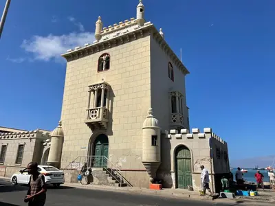 a small white building with green doors on a street at Casa Maré & Museu - Porta Nº 18 in Mindelo