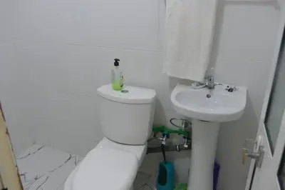 a white bathroom with a toilet and a sink at Magei in Tarrafal