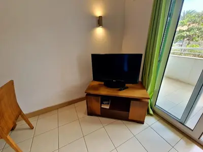 a television on a table in a room with a window at Stay, laugh, repeat! in Prainha