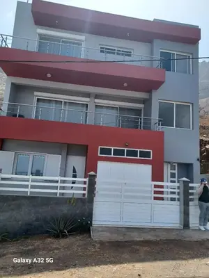a woman standing in front of a house at Casa Larinha in Ponta do Sol