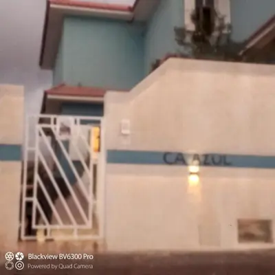 a white train car with a gate in front of a building at Ca Azul in Tarrafal