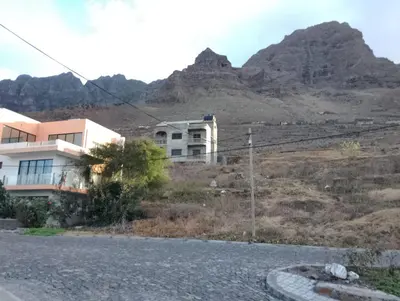 a house on the side of a road with mountains in the background at ApartamentoT1 Ponta do Sol in Ponta do Sol