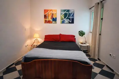 a bedroom with a large bed with a red pillow at Cozy kriol stay, steps to ocean in Praia
