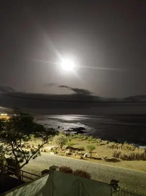 a full moon rising over a beach with the ocean at brISA in Praia