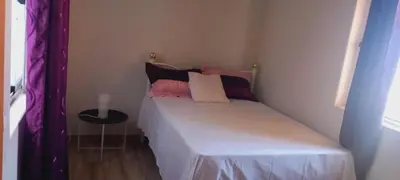 a small bedroom with a bed with pillows and a table at Relache House Praia in Praia