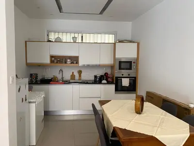 a kitchen with white cabinets and a table with a tableablish at Infinito house in Praia