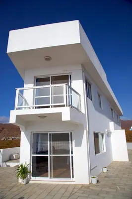 a white house with a balcony on top of it at Cacimba Sunset Lodge in Tarrafal