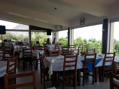 a restaurant with white tables and chairs and windows at Quinta Da Montanha in Rui Vaz
