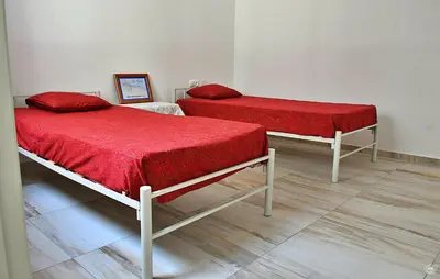 two beds with red covers in a room at Casa Magui de Reis in Tarrafal
