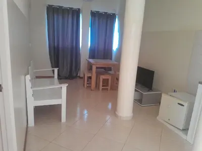 a living room with a table and a chair and a television at Casa Magui de Reis in Tarrafal