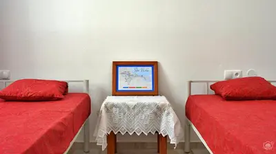 a room with two beds and a table with a picture at Casa Magui de Reis in Tarrafal