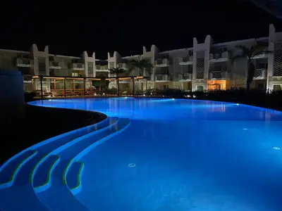 a large swimming pool in front of a hotel at night at Ocean & Pool - 2 bedroom Apartment in Santa Maria