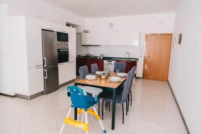 a kitchen with a table and chairs in a kitchen at T2 amplo com ar condicionado e perto da praia in Praia