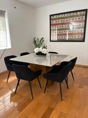 a dining room table with black chairs and a vase of flowers at Prainha Beach House in Praia