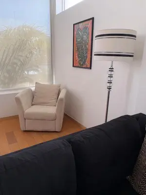 a living room with a couch and a chair and a lamp at Prainha Beach House in Praia