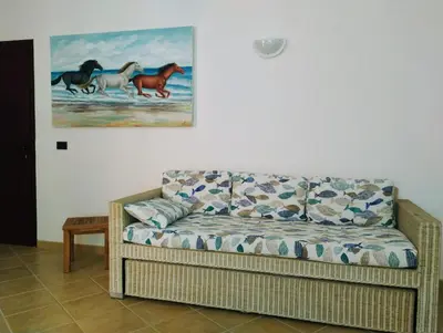 a couch in a living room with a painting on the wall at Greta Apartment in Santa Maria