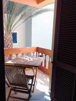 a wooden table and a chair on a balcony at Greta Apartment in Santa Maria