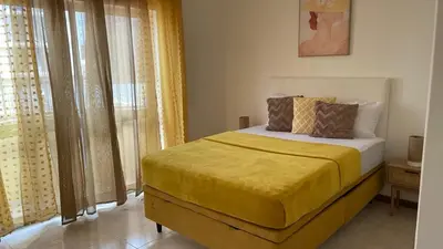 a bedroom with a bed with yellow sheets and a window at Appartement 3 chambres tout confort in Praia
