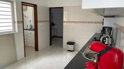 a kitchen with a sink and a red chair at Appartement 3 chambres tout confort in Praia