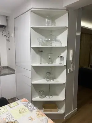 a white cabinet with dishes on it next to a bed at Apartamento de Luxo -T2 in Praia