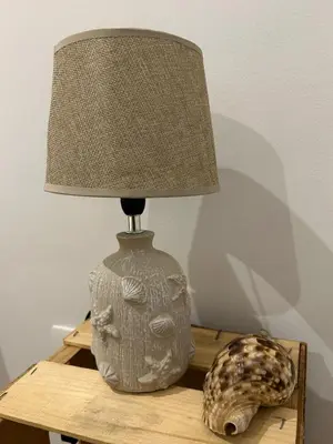 a lamp on a wooden table with a shell next to it at Kubiku Guest House in Praia