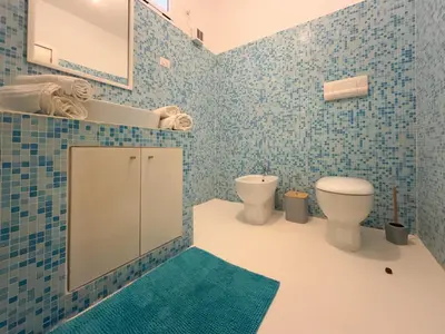 a blue tiled bathroom with a toilet and a mirror at I LOVE BOA VISTA - Seafront Apartments in Sal Rei