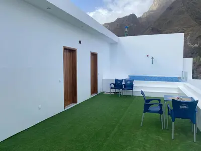 a room with a green floor and chairs and mountains at Laranjinha Rooms in Paul