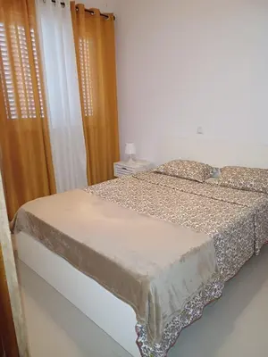 a bed in a white room with curtains and a bed sidx sidx sidx at L&E Apartment in Mindelo