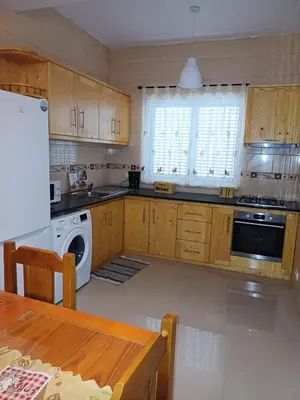a kitchen with wooden cabinets and a white appliance at L&E Apartment in Mindelo