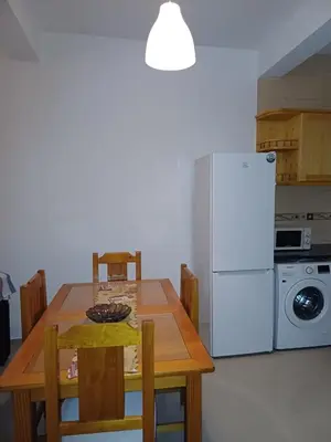 a kitchen with a wooden table and a white refrigerator at L&E Apartment in Mindelo
