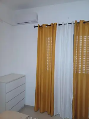 a bedroom with an orange and white curtain and a dresser at L&E Apartment in Mindelo