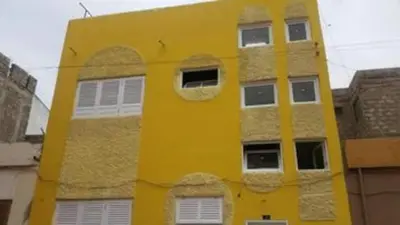 a yellow building with white windows and an arch at Casa da Lalá - casa com 3 quartos e espaços exteriores! in Mindelo