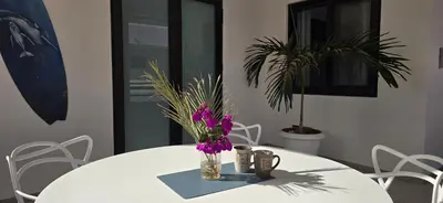 a white table with a vase with purple flowers on it at Ocean Breeze in Sal Rei