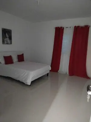 a bedroom with a bed with two red curtains at Residencia Moreno in Praia