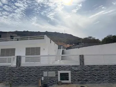 a large white building with a hill in the background at Residencia Moreno in Praia