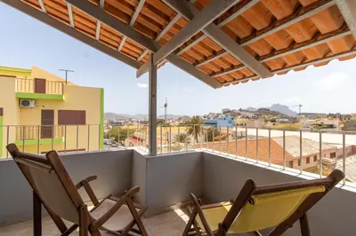 two chairs on a balcony with a view of a city at Maya Mindelo 4 in Mindelo