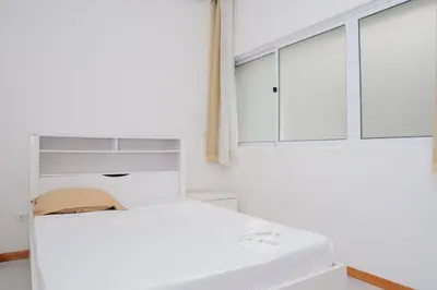 a white bedroom with a bed and a window at Your Escape Home in Praia in Praia