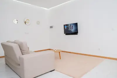 a living room with a chair and a tv on a wall at Your Escape Home in Praia in Praia